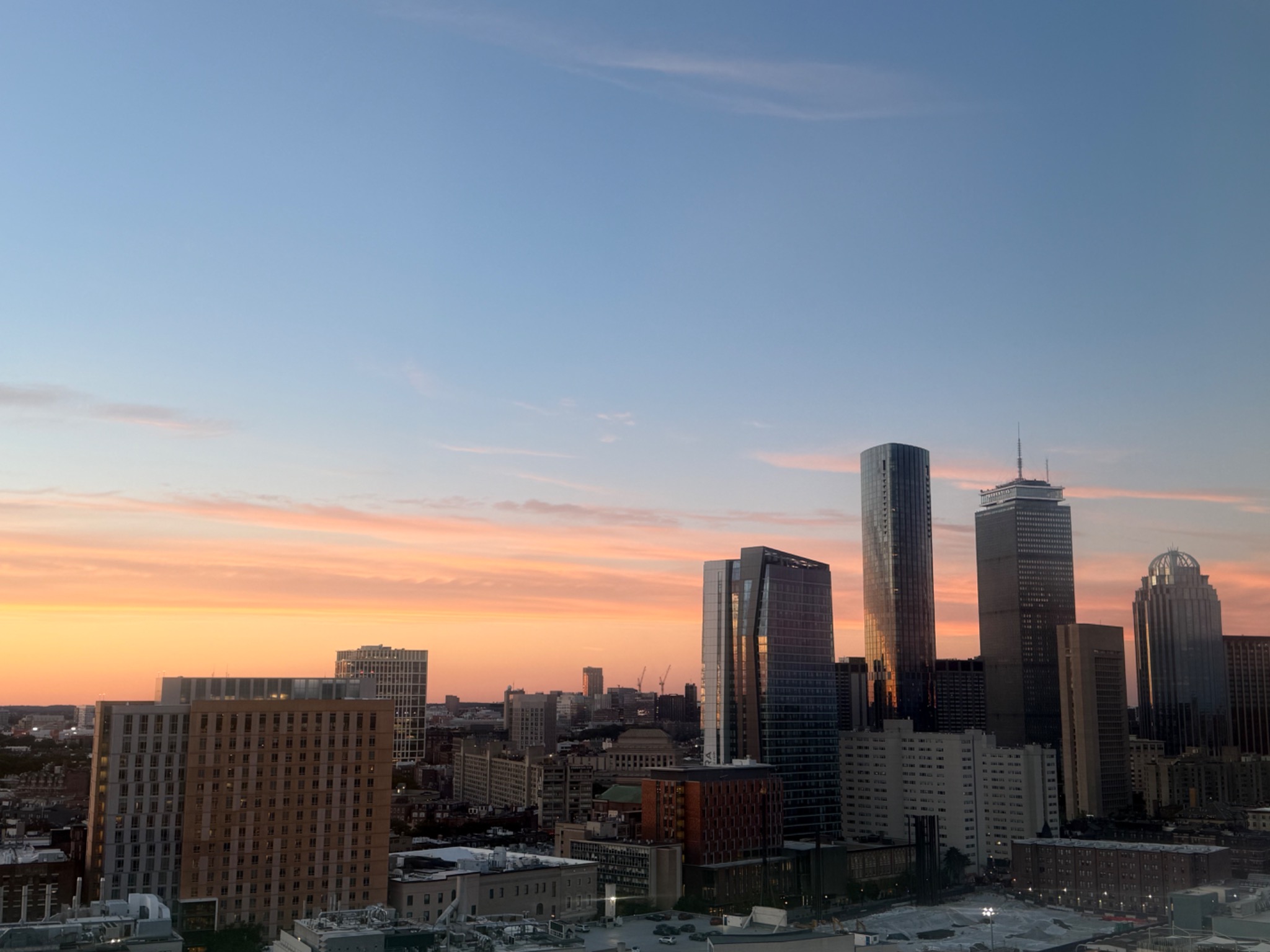 Boston skyline beneath a blue sky and warm orange sunset